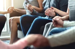 Adults holding hands in group therapy as part of outpatient rehab program
