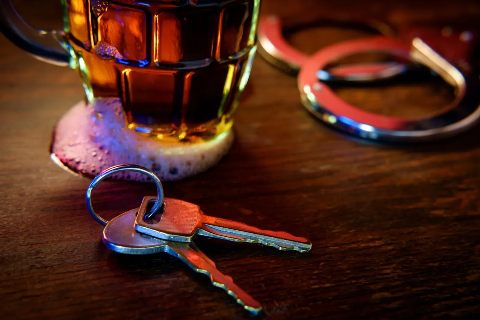 Mug of frothy beer with handcuffs and keys symbolizing drunk driving arrest