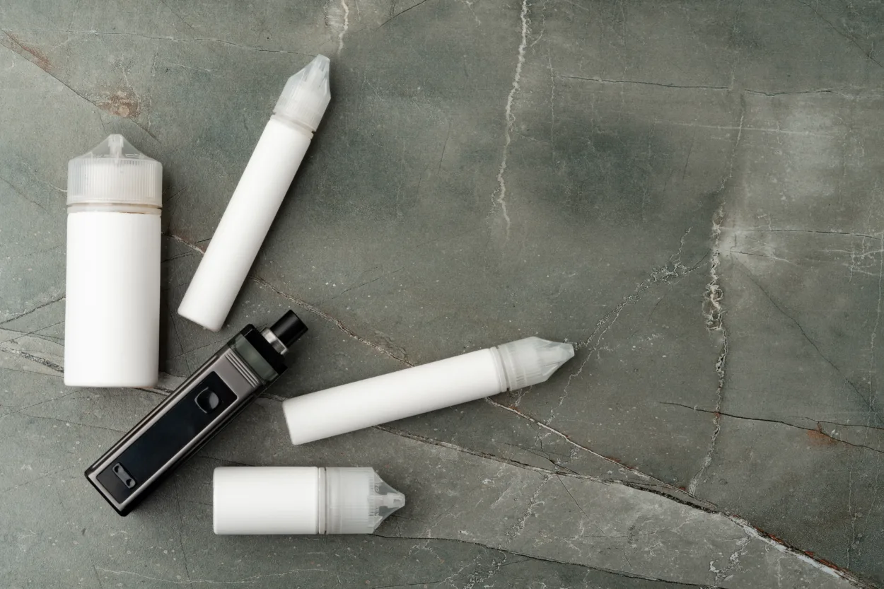 Electronic cigarette with re-fill liquid bottles on gray background close up