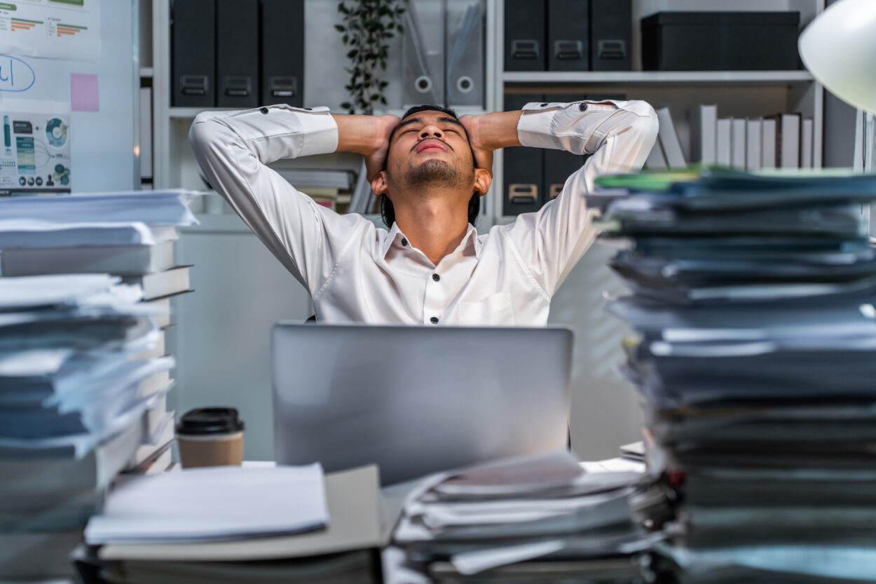 Frustrated young businessman worker working on table in office. Busy employee worker people feel tired and headache from late work and overwork job document on computer desk at company workplace