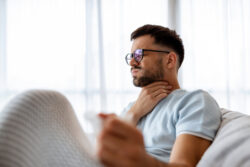 Man holding his throat after its sore from smoking weed