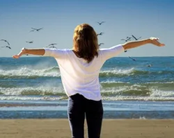 woman with outstretched arms on beach