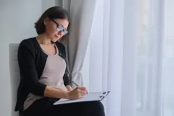 Woman sitting down filling out a list on a clipboard