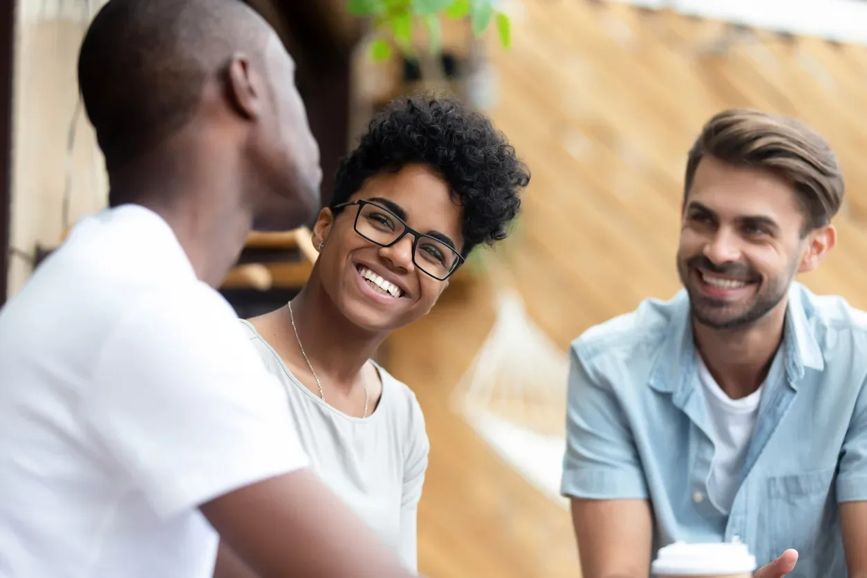 Happy multiethnic young people relax together have fun talking and chatting sharing ideas, smiling multiethnic diverse friends speak resting hanging out in coffeeshop. Communication concept