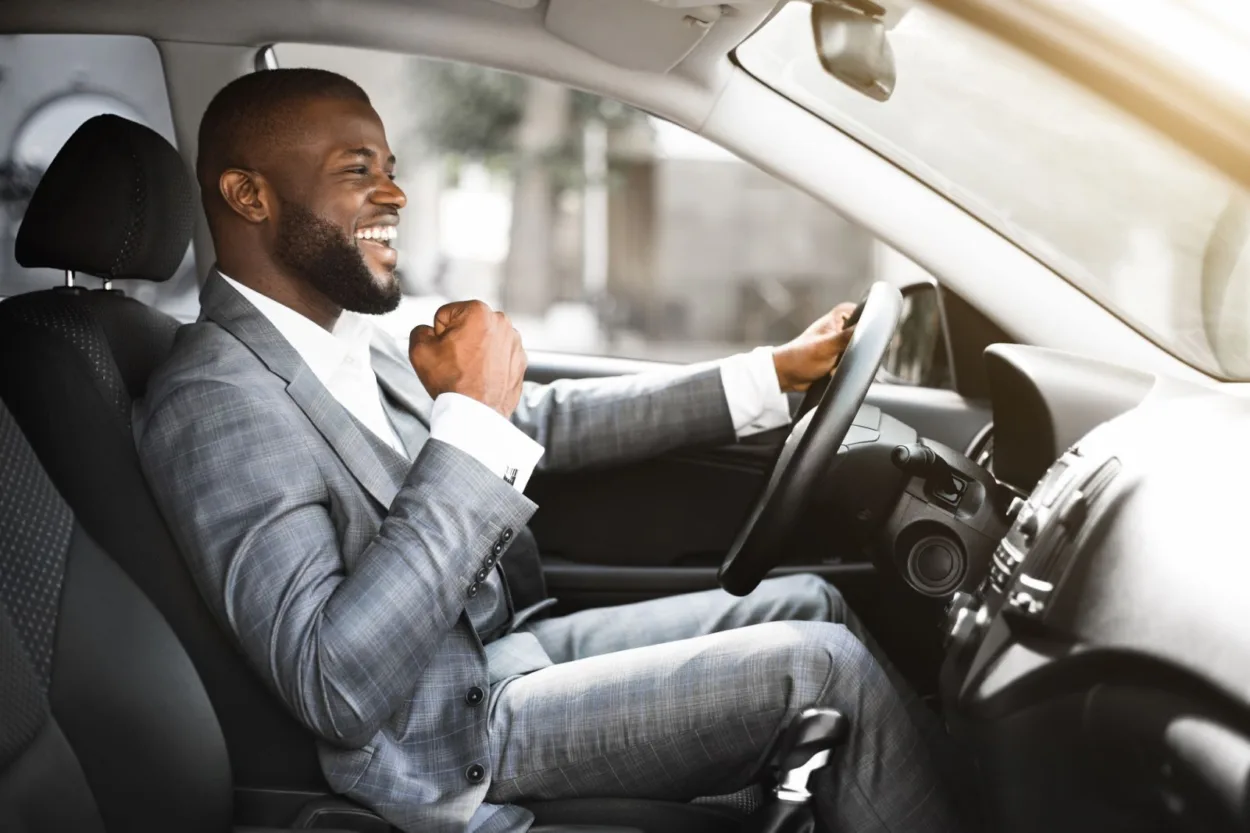African American male driving his car and pumping his fist in joy