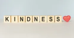 Kindness Word Written In Wooden Cube on a light background