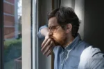 Portrait of one guy longing and looking through window