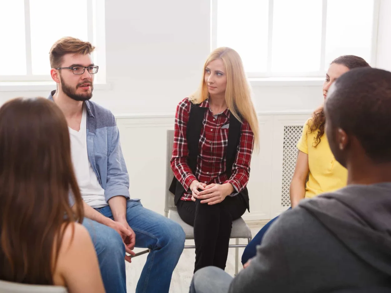 People sit in a circle during a group therapy session