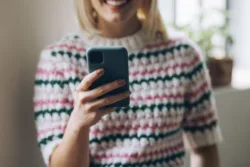 an-anonymous-businesswoman-typing-text-message-on-her-smartphone-while-standing-in-a-living-room-stockpack-gettyimages An anonymous businesswoman typing text message on her smartphone while standing in a living room