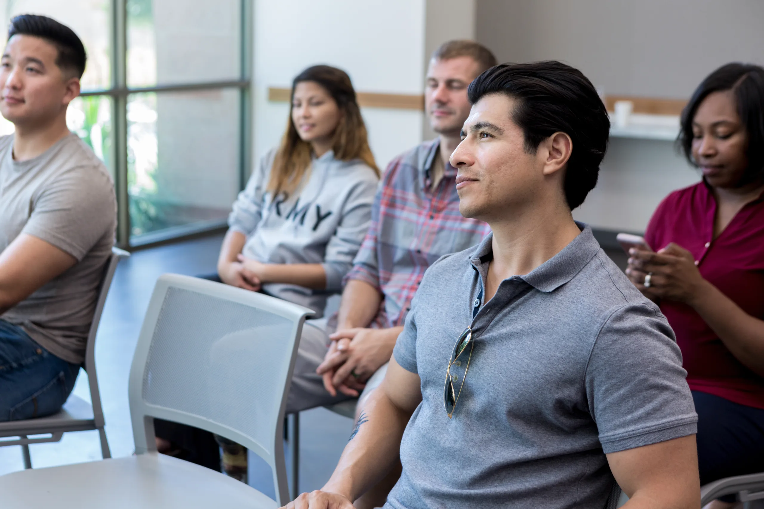 An audience of military veterans attend a seminar for veterans. They are listening attentively to the speaker.