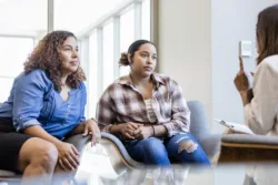 During their family counseling session, the unrecognizable female therapist gestures while she talks to the mother and daughter about communication skills.
