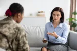 Female Psychotherapist Talking To Black Military Lady During Therapy Session In Office, Professional Psychologist Counselling African American Soldier Woman Suffering From Mental Disorder And PTSD