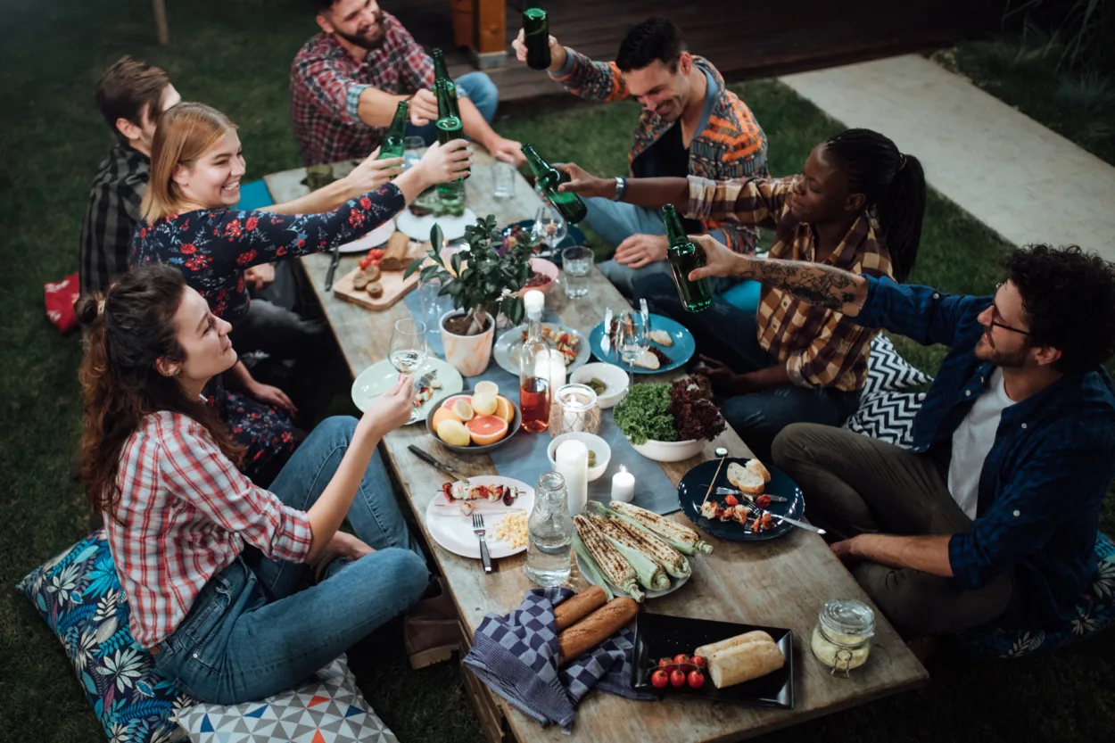 Friends toasting with wine and beer at rustic dinner party