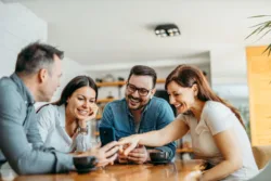 Group of friends sitting around a table looking at something on a cell phone
