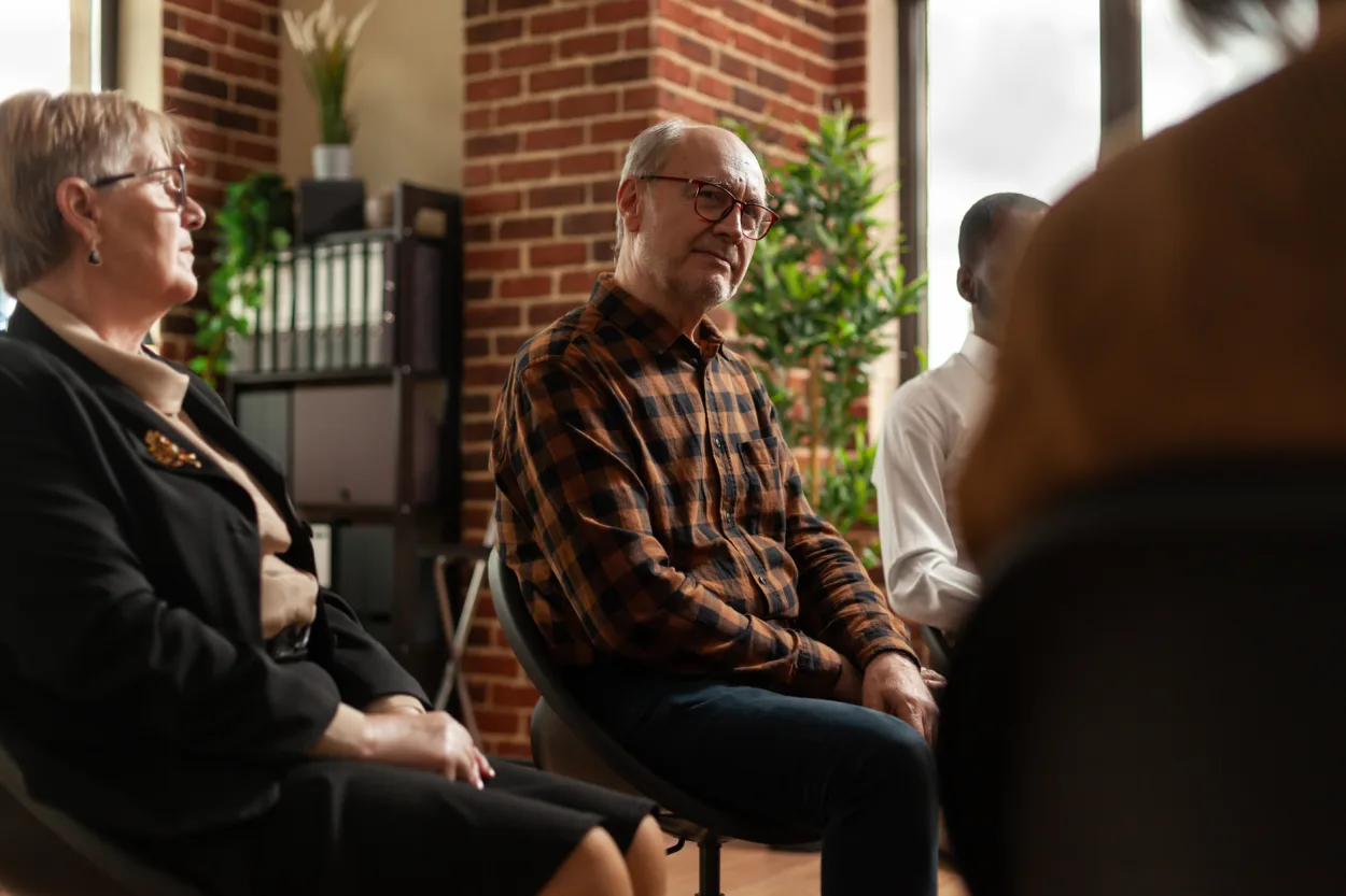 People talking to therapist at aa group therapy meeting, sharing addiction problems. Multi ethnic patients having discussion about alcohol issues with specialist at support session program.