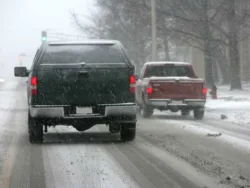 Two trucks driving on a snowy road