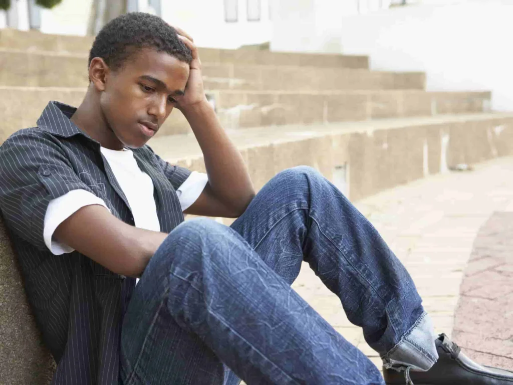 A stressed out college student sits on the ground with his head in his hands