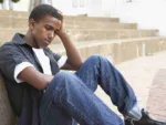The Mental Health Crisis Among College Students A stressed out college student sits on the ground with his head in his hands
