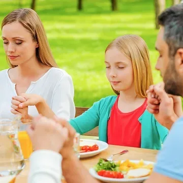 family sitting at picnic and praying