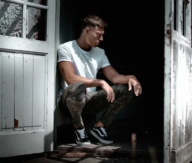man crouching against door