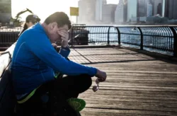 Drug Addiction Distressed middle aged man sits cross-legged on a bench.