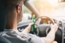 Drunk driver drinking behind the steering wheel of a car