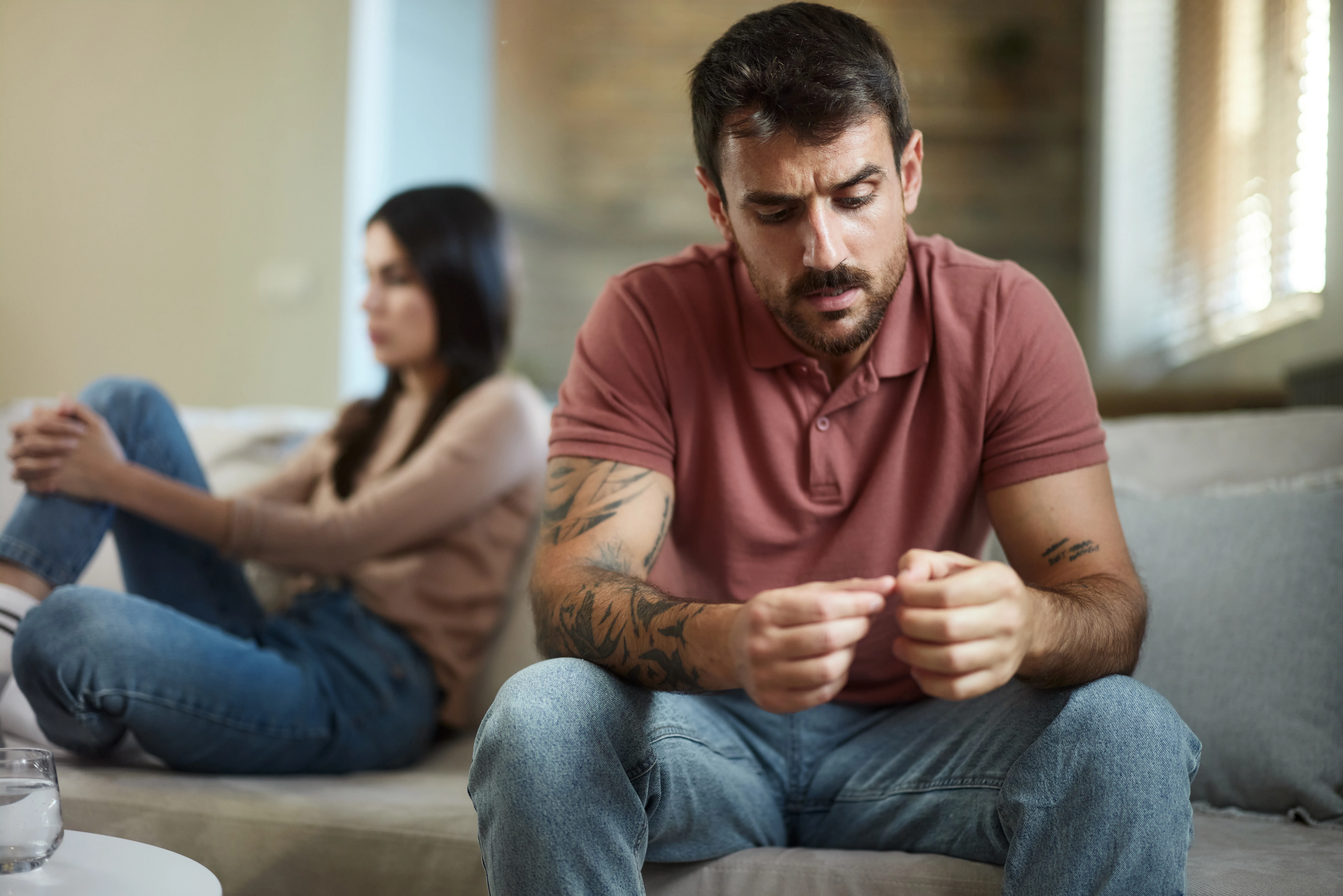 Worried man feeling sad after having a fight with his girlfriend in the living room.