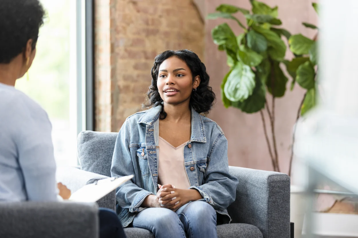 Young adult woman sits, talking with therapist during a counseling session.