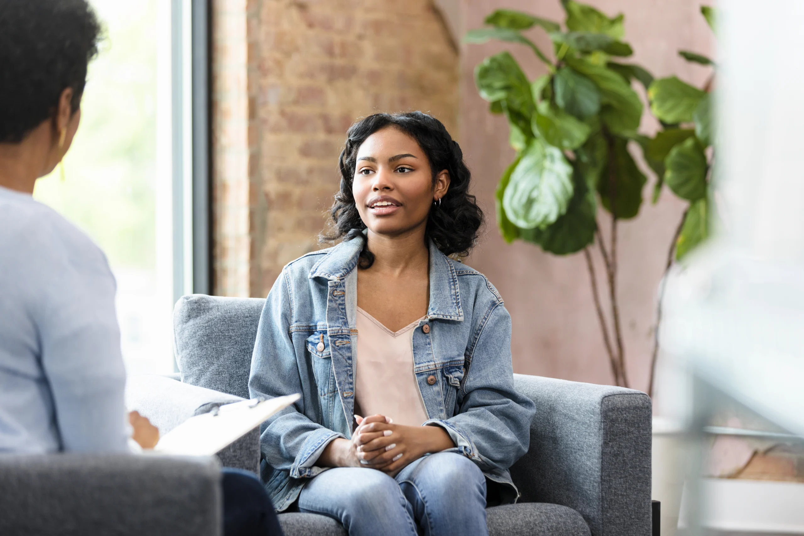 Young adult woman sits, talking with therapist during a counseling session.