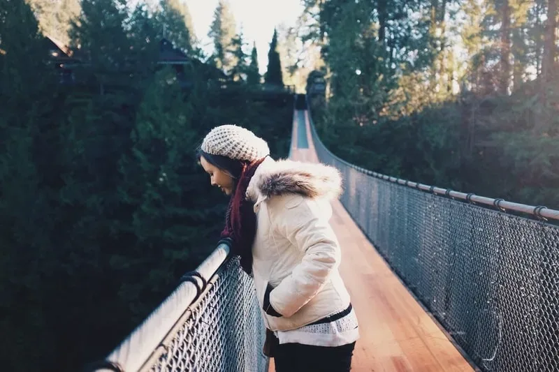 Woman with fear of heights uses exposure therapy by standing on a bridge