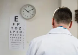 doctor in office with vision chart on wall