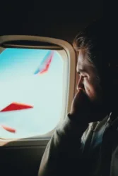 man staring out airplane window