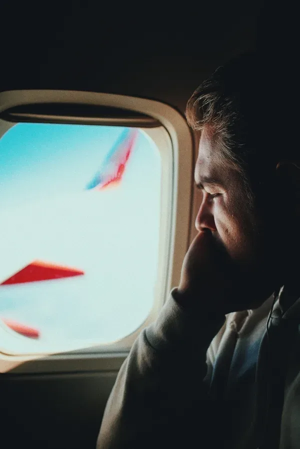 man staring out airplane window