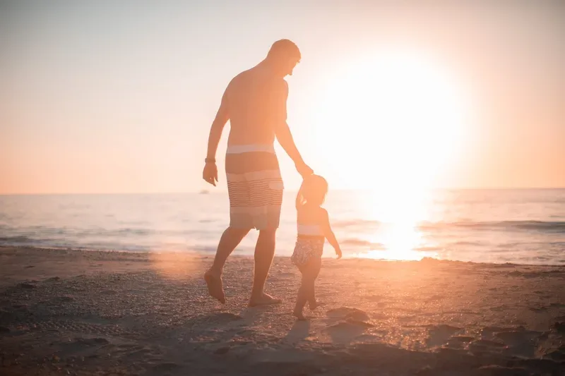 man and daughter walk on beach