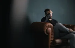 man covering face with hands sitting on couch