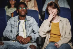 Young man and his female friend watching a movie about addiction